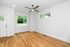 Bright and airy room featuring elegant hardwood floors, large windows with scenic views, and a modern ceiling fan.