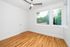 Bright room with large windows, gleaming hardwood floors, and a modern ceiling fan offering a serene outdoor view.