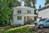 Charming two-story house with a welcoming front porch, nestled in a lush green neighborhood, perfect for family living.
