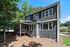 Charming two-story home with elegant dark siding, featuring covered porch and surrounded by lush greenery.