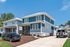 Charming two-story suburban home with a modern blue facade, spacious driveway, and well-maintained front yard under a clear blue sky.