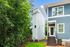 Charming modern home with vibrant blue siding, nestled beside lush greenery for serene living.