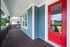 Charming porch with a vibrant red door and elegant dark wood decking, complemented by blue and white exterior paneling.