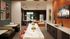 Modern communal living space featuring a sleek kitchen area, stylish lounge with plush seating, vibrant art decor, and ambient lighting for ultimate comfort and style.