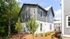 Charming modern townhouse exterior with stylish contrasting siding surrounded by lush greenery, perfect for serene living.