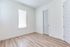 Bright and airy room with sleek hardwood floors, modern white trim, and abundant natural light from a large window with blinds.