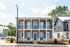 Charming two-story duplex with modern gray facade, inviting balconies, and lush landscaping in a serene neighborhood.