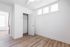Bright and modern bedroom with sleek white walls, elegant closet space, and sunlit windows, perfect for a cozy retreat.