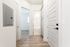 Bright hallway with modern finishes, showcasing sleek wooden flooring and white paneled doors, leading to a sunlit room and a pristine bathroom.