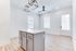 Bright open-concept kitchen with sleek island, contemporary light fixture, and elegant hardwood flooring.
