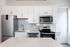 Modern kitchen featuring sleek white cabinetry, stainless steel appliances, and elegant marble countertops.