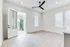 Bright and spacious room with elegant wooden floors, large windows, and a modern ceiling fan, opening to a charming balcony.