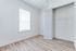 Bright room with window and spacious closet, featuring modern wood flooring and elegant white walls.