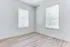 Bright and airy room with two large windows and elegant wood laminate flooring, perfect for a cozy bedroom or home office.