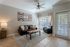 Inviting living room with elegant tile flooring, cozy black leather seating, decorative pillows, soft ambient lighting, and vibrant artwork.