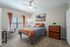 Inviting bedroom with modern decor, featuring a cozy bed, stylish artwork, and warm natural light through large windows.