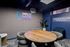 Modern meeting room with a round wooden table, comfortable chairs, and vibrant neon sign reading 'Live On Air,' ideal for creative discussions at Venue & Villas on Guadalupe.