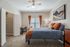 Inviting bedroom with plush carpeting, elegant ceiling fan, and cozy decor, including accent pillows and vibrant curtains.
