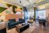Modern living space with stylish furnishings, featuring a plush teal sofa, chic accent chair, and a spacious open layout with ample natural light.