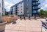 Modern apartment courtyard with stylish lounge chairs, outdoor grill, and string lights, perfect for relaxation and entertaining.