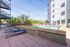 Charming outdoor pool area with stylish lounge chairs, surrounded by a modern apartment building and lush greenery.