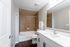 Modern bathroom featuring sleek marble countertop, elegant white vanity, and inviting bathtub with stylish tile surround.
