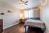 Cozy bedroom with stylish decor, featuring warm lighting, a ceiling fan, and modern furnishings, perfect for relaxation.