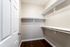 Spacious walk-in closet with sleek white shelving and elegant hardwood floors, offering ample storage in a modern apartment.