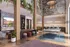 Contemporary urban apartment lounge with vibrant decor, featuring a stylish media area, lush greenery, and a sleek kitchen with high stools.