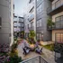 Modern urban courtyard with vibrant landscaping, featuring cozy fire pit seating area and elegant apartment balconies.