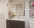 Modern bathroom featuring a sleek design with dark wood vanity, illuminated mirror, and stylish decor accents.