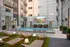 Modern apartment courtyard featuring a stunning pool area with stylish lounge chairs, lush greenery, and a large outdoor screen for entertainment.
