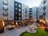 Chic modern apartment courtyard featuring cozy fire pit seating, vibrant landscaping, and a stylish recreation area.