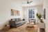 Chic modern living room with a cozy gray sofa, vibrant rug, sleek furniture, and large window for natural light.