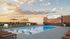 Luxurious rooftop pool with lounge chairs and an outdoor big screen overlooking a stunning sunset.