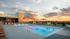 Luxurious rooftop pool area with sun loungers, modern architecture, and stunning sunset views.
