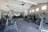 Modern fitness center equipped with treadmills, stationary bikes, and weight machines, featuring bright natural lighting and spacious layout.