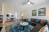 Inviting living room with a modern sectional sofa, vibrant patterned rug, stylish artwork, and an open-plan dining area.
