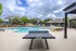 Inviting outdoor pool area with modern lounge chairs, a ping pong table, and lush greenery, perfect for relaxation and entertainment.