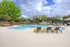 Inviting outdoor pool area with modern lounge chairs, vibrant greenery, and a serene ambiance, perfect for relaxation and leisure.
