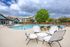 Inviting outdoor pool area with modern lounge chairs, lush greenery, and stylish apartment buildings in the background.