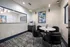 Modern office meeting room featuring sleek black chairs around a round marble table, abstract artwork, and a minimalist design.