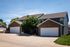 Charming suburban duplex with brick fa&ccedil;ade and double garages, set against a clear blue sky.