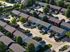 Charming residential neighborhood with colorful townhouses, lush greenery, and spacious driveways nestled in a peaceful suburban setting.