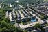 Charming aerial view of a lush residential neighborhood with rows of homes, vibrant greenery, and a sparkling community pool.