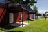 Charming red-sided apartments with private balconies and vibrant green lawns, perfect for outdoor relaxation.