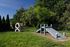 Charming outdoor play area featuring a unique wooden ramp and creative tire obstacle, set within lush greenery.
