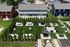 Charming aerial view of a modern apartment complex with vibrant green lawns, cozy hammocks, and inviting outdoor seating areas featuring umbrellas and picnic tables.