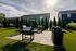 Charming outdoor space with lush greenery, modern grills, and relaxing hammocks under a sunny sky.