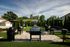 Inviting outdoor barbecue area with multiple grills, shaded tables, and lush greenery, perfect for social gatherings and relaxation.